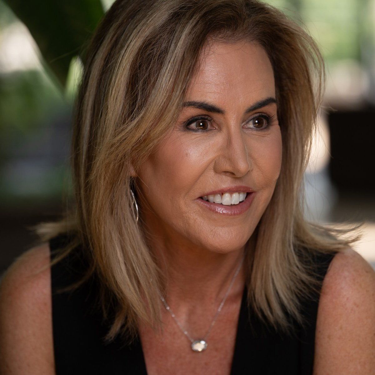 Smiling woman outdoors with blurred background.